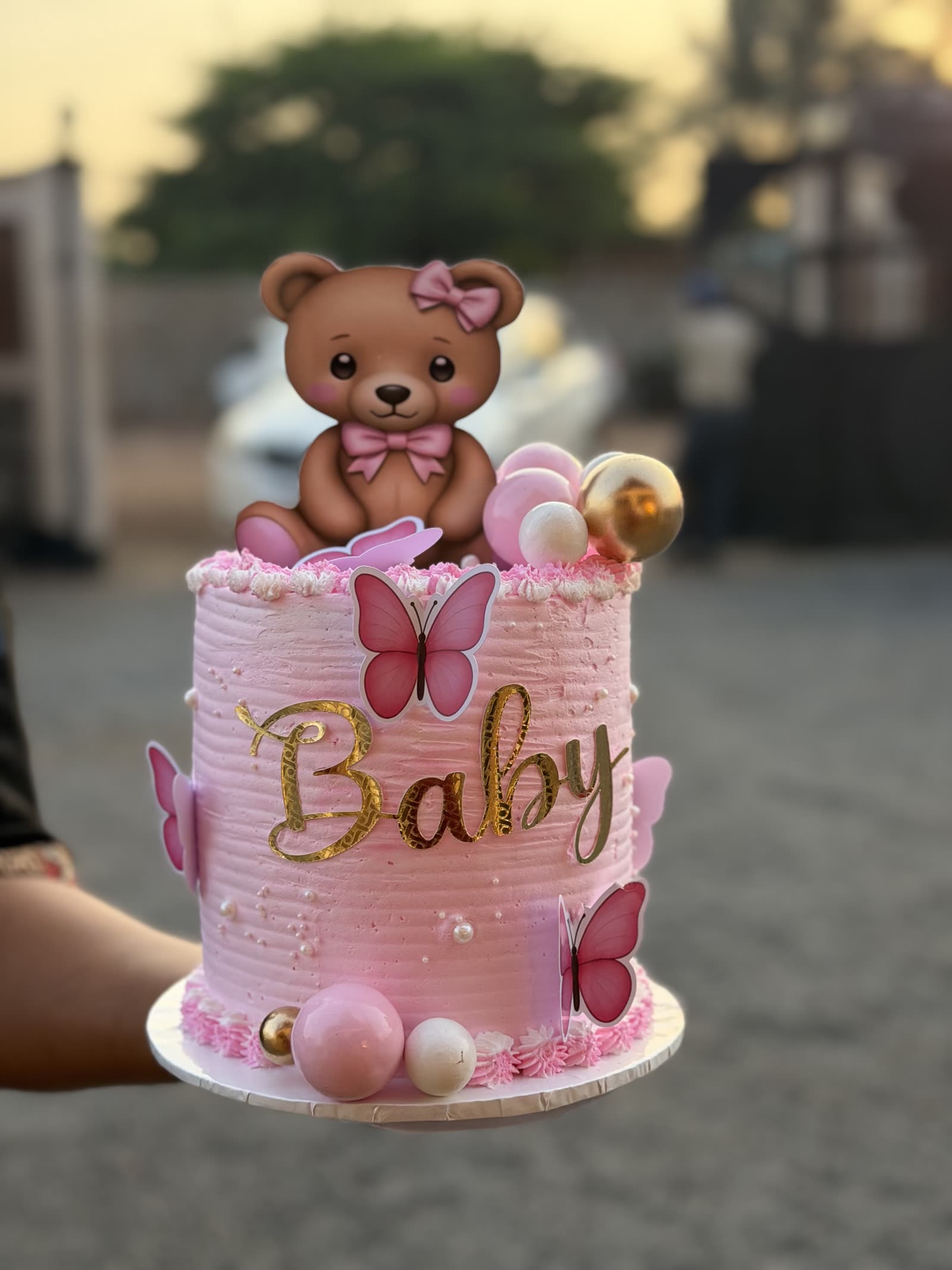 Pink baby shower cake with a teddy topper, butterflies and gold lettering