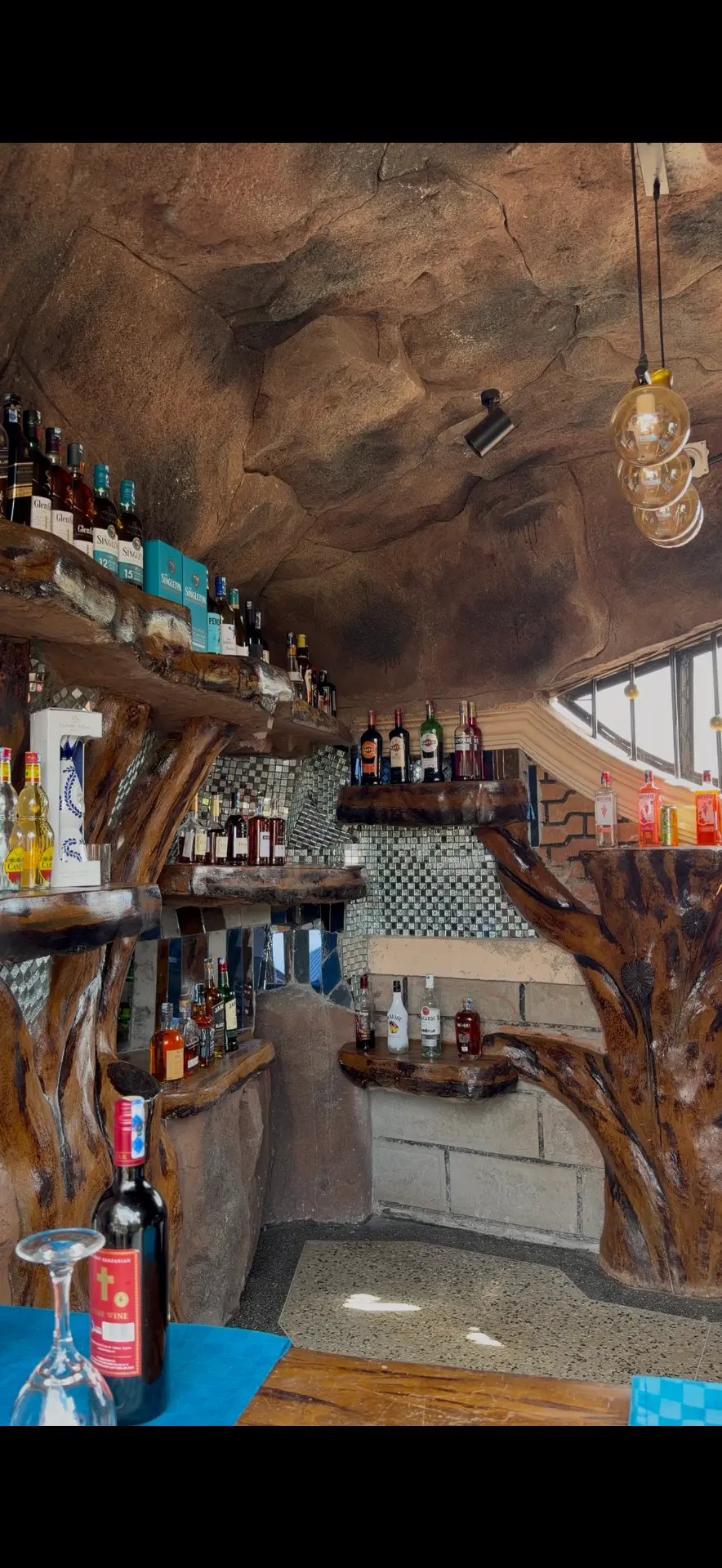 Tiered wooden bar shelving with glass mosaic accents and a curated selection of spirits