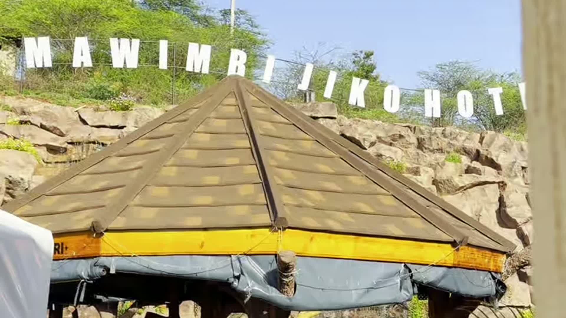 Thatched gazebo beneath the Mawimbi Jiko Hotel signage in the landscaped grounds
