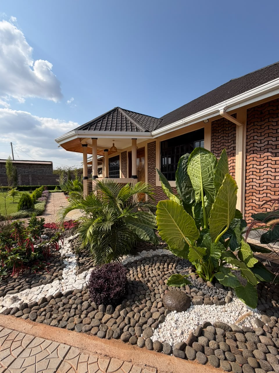Covered veranda outside the conference hall framed by palms, tropical planting and river-stone landscaping