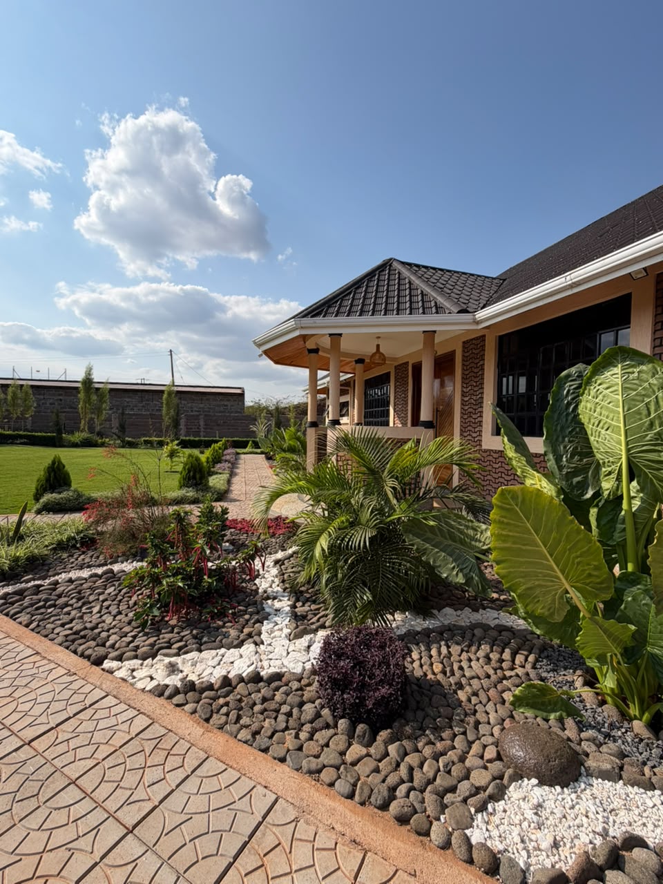 Wide view of the conference hall veranda, pebble gardens and open lawn under clear Taveta skies