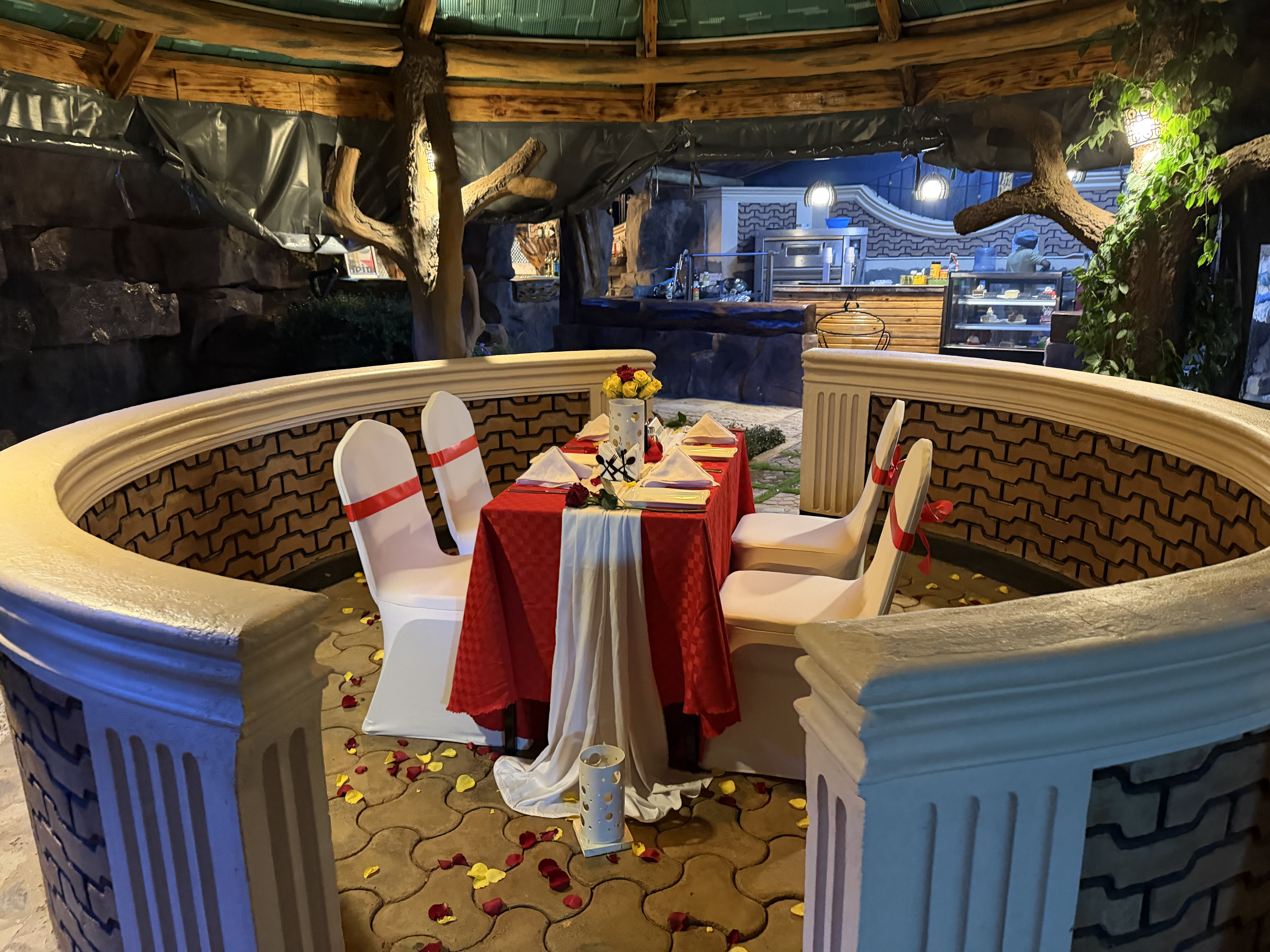 Private gazebo dinner set with rose petals and candles against the wave brickwork