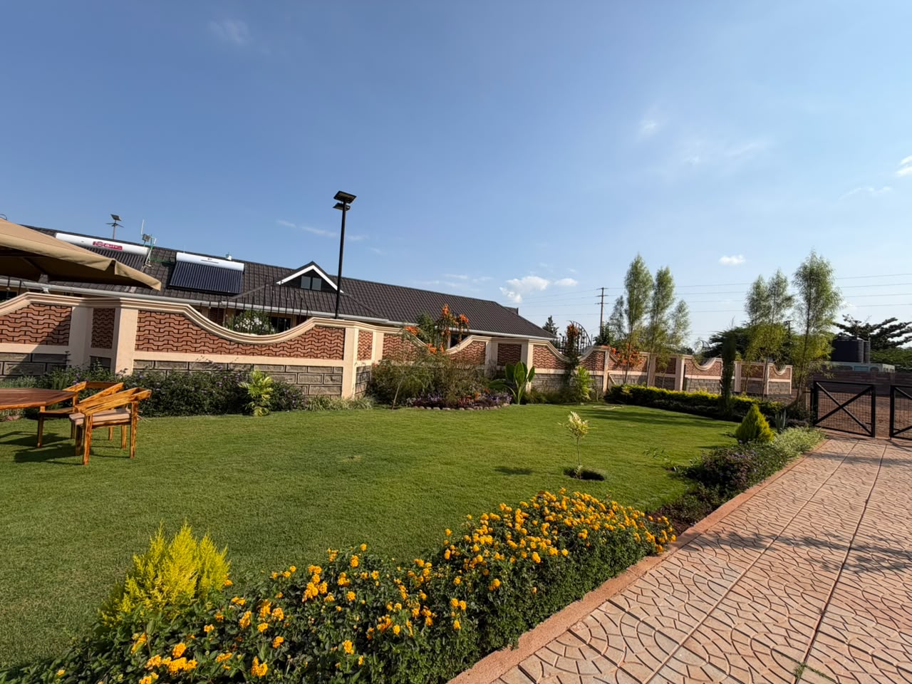 Manicured lawn and marigold beds beside the wave-patterned perimeter wall of the conference grounds