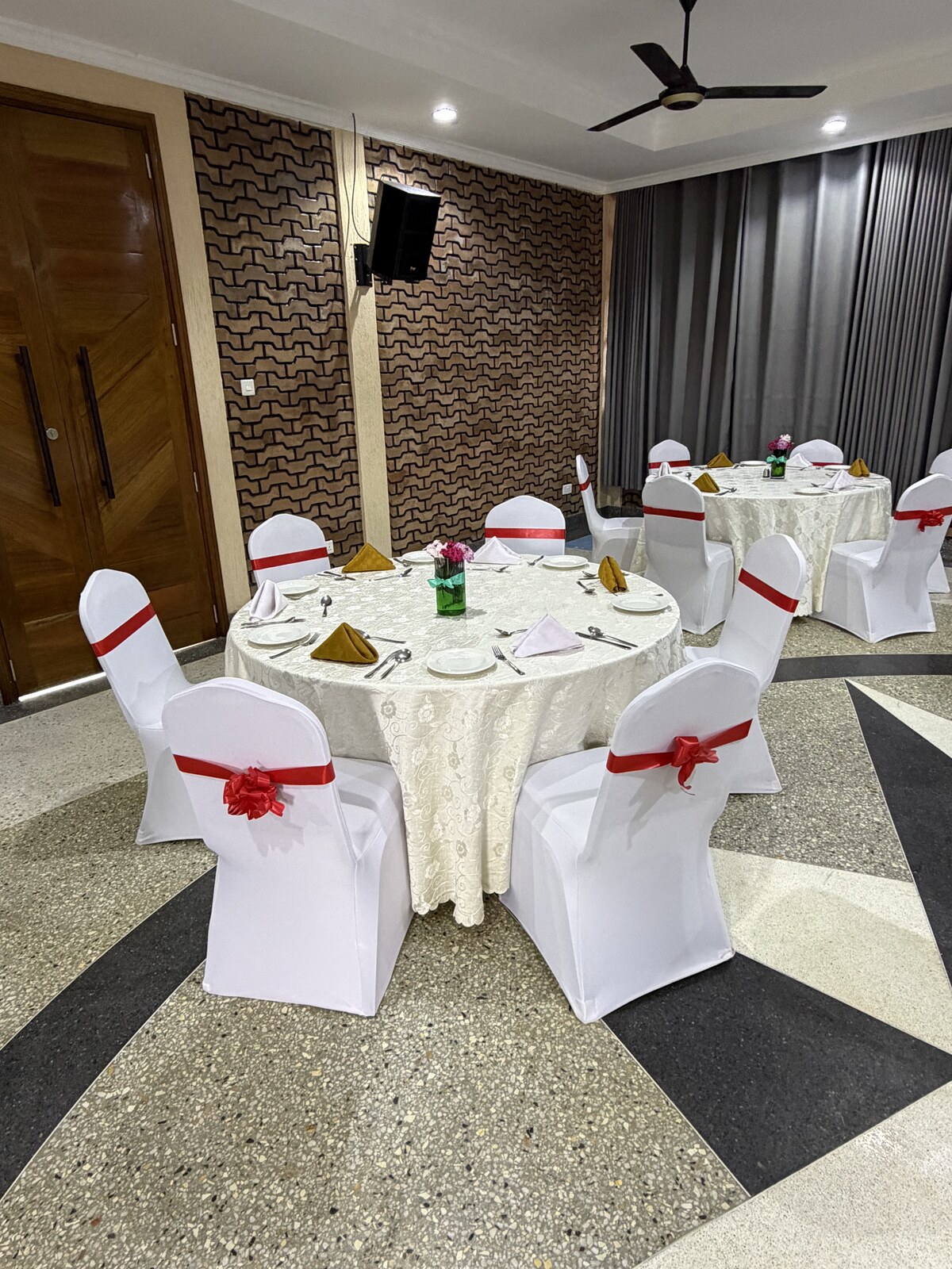 Round tables dressed in white linen with ribboned chair covers in the Mawimbi Jiko dining hall