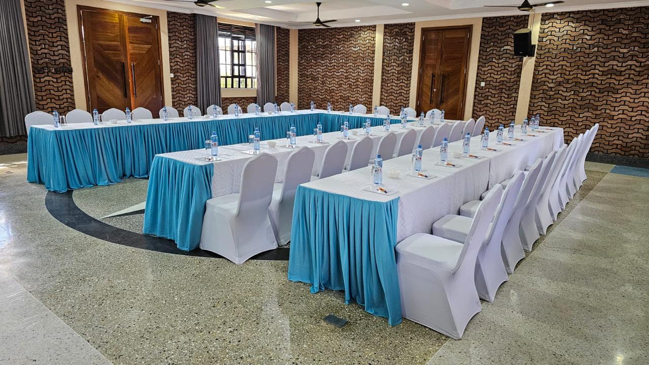 Wide U-shape conference setup facing carved timber doors in the Mawimbi Jiko hall