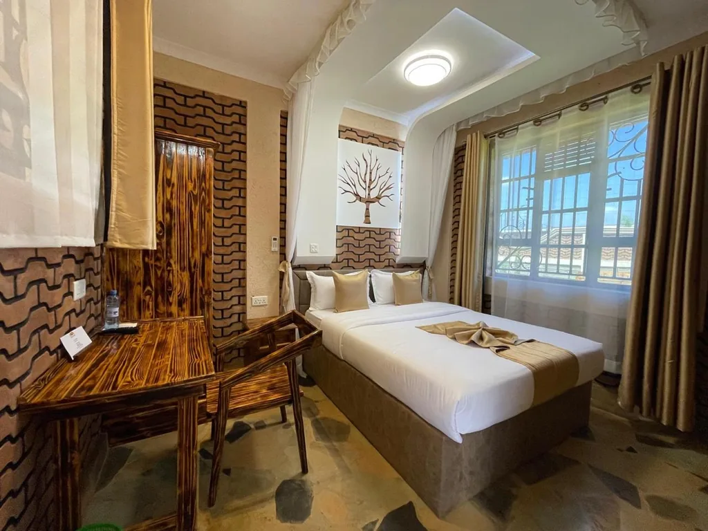 Guest room with a wooden work desk and chair, canopy netting and the carved boabab panel above the bed