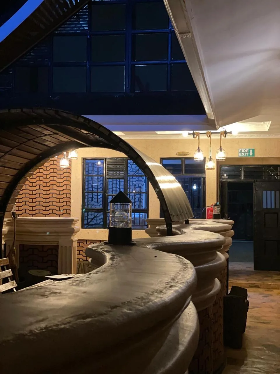 Curved bar counter and brick archway in the Mawimbi Jiko lounge, lit warmly in the evening