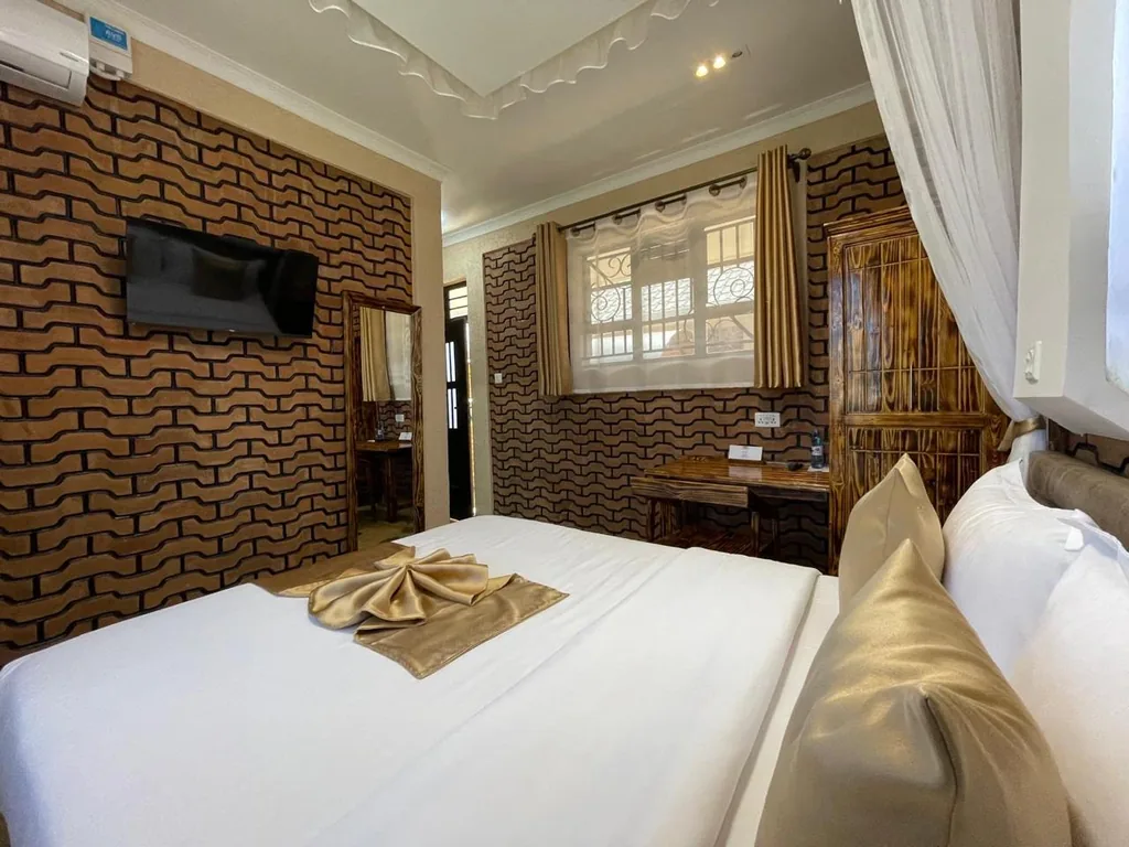Double room with gold satin linen detail, Smart TV on the wave-brick wall and a timber wardrobe